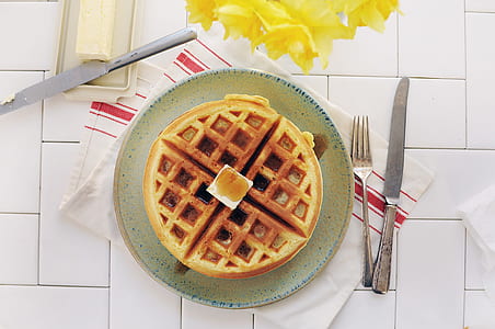 top view photography of plate of Belgian waffle beside silver fork and butter knife and yellow daffodil flowers thumbnail