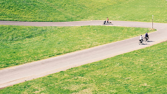 two people on bicycle riding on road between green lawn thumbnail