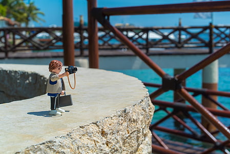 selective focus photography of man holding camera figurine thumbnail