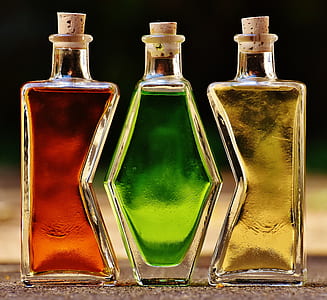 three clear glass bottles with yellow, green, and red liquids thumbnail