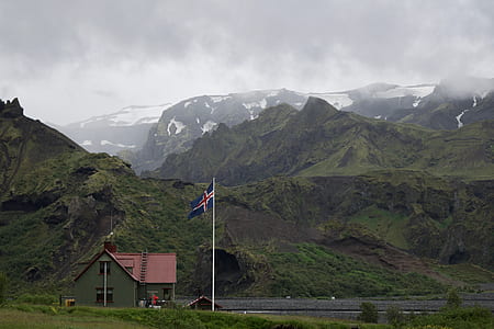 blue and red cross flag with pole near gray house in front of river thumbnail