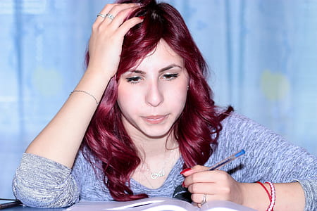 woman wearing gray space-dyed scoop-neck sweatshirt holding blue ballpoint pen while reading a book thumbnail