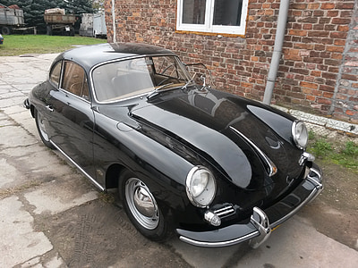 parked black Volkswagen beetle beside brick wall thumbnail