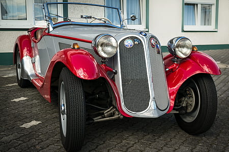 classic gray and red vehicle parked near white building at daytime thumbnail