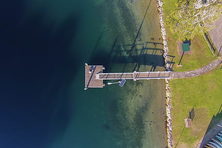 aerial photography of brown wooden dock near blue body of water at daytime thumbnail