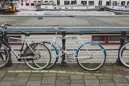 white and blue city bicycle leaning on black steel fence thumbnail