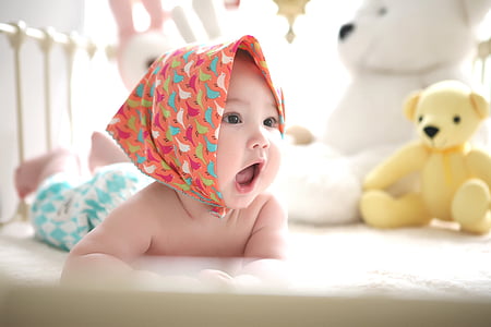 baby with pink head scarf prone lying in crib thumbnail