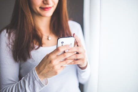 Close up portrait of a young woman typing a text message on mobile phone thumbnail