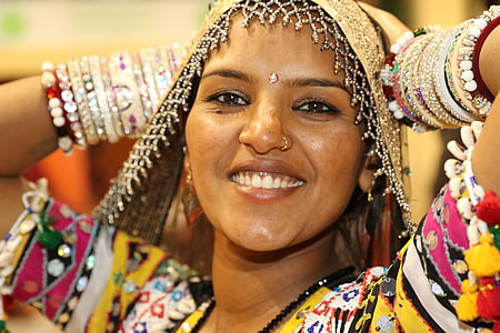 woman wearing gold scarf and yellow, black, pink, and green top thumbnail