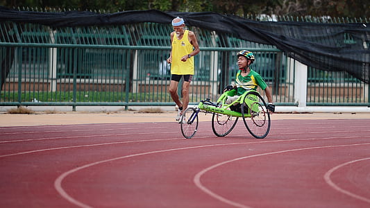 man wearing yellow tank top jogging on track in field thumbnail