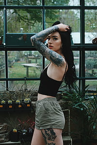 woman in black spaghetti strap crop-top and gray short shorts standing near black metal and glass partitio thumbnail