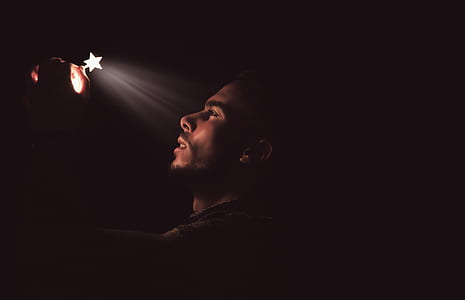 man wearing gray shirt holding white light close-up photo thumbnail
