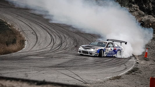 black and white Nissan 240SX drifting on curve near traffic cone on hill thumbnail