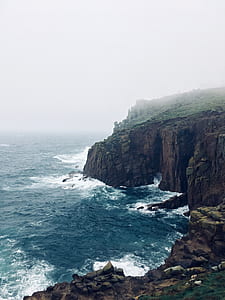 brown and green cliff beside blue sea thumbnail