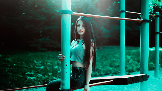 woman wears grey sleeveless crop top and black jeans seats on grey concrete chair thumbnail
