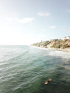 person laying down on surfboard on sea during daytime thumbnail