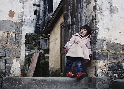 girl in gray coat leaning on gray concrete house thumbnail