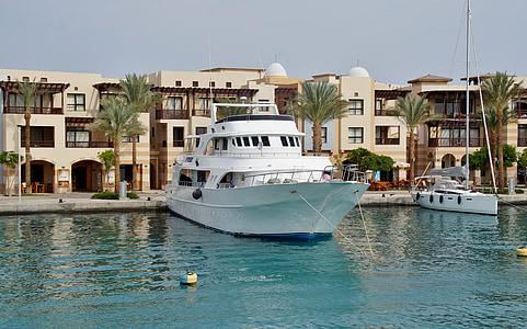 white yacht on water beside building thumbnail