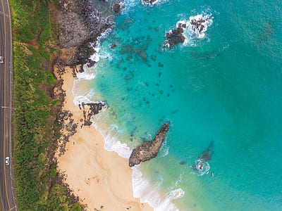 rock formation on seashore near trees and road in aerial photography thumbnail