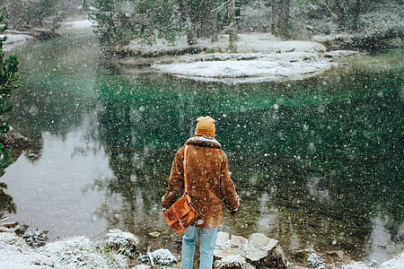 person facing body of water under falling snow thumbnail