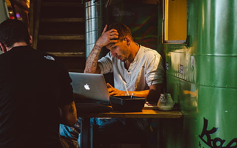 man using silver MacBook while holding his head thumbnail