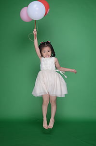 girl jumping while holding party balloons thumbnail