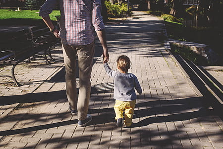 man walking together with child at the park during daytime thumbnail