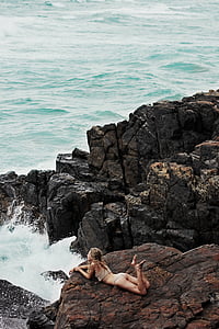 woman lying on rock beside body of water thumbnail