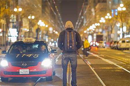 man wearing hoodie and backpack standing on middle of road thumbnail