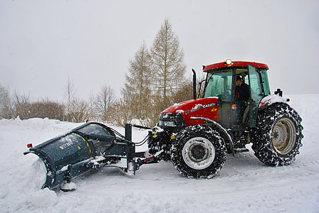 photo of man riding on black and red tractor with black snow plow blade thumbnail