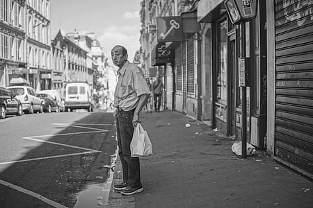 grayscale photography of man holding pack beside street thumbnail