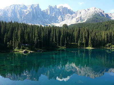photography of lake surrounded by green pine trees next to snow capped mountain during daytime thumbnail