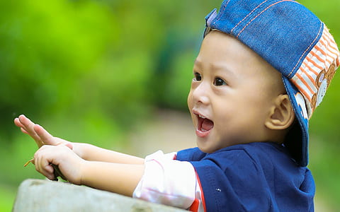 selective focus of smiling boy in blue cap outdoors thumbnail