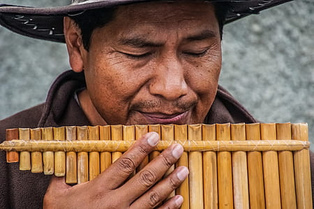man wearing brown hat while blowing pan flute thumbnail