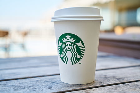 tilt shift lens photography of Starbucks cup on gray wooden surface thumbnail
