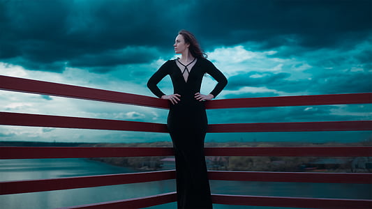 woman wearing black dress leaning on red railings thumbnail