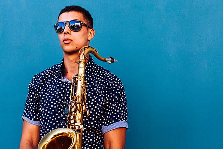 man holding saxophone with green background thumbnail