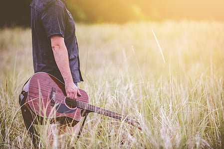 man holding acoustic guitar on grass thumbnail