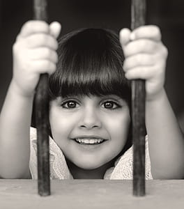 smiling girl behind bars thumbnail