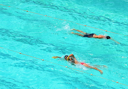 two persons swimming back and forth in swimming pool thumbnail