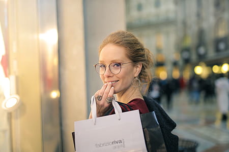 A young blonde woman wearing a red velvet dress holding shopping bags in her hand thumbnail