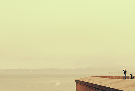man and woman on brown wooden dock near ocean during daytime thumbnail
