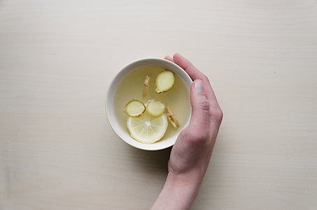 person holding white ceramic bowl with sliced lemon thumbnail