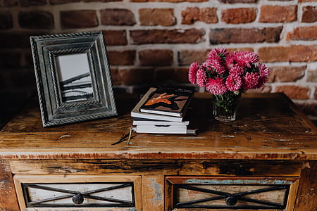 Photo frame, books and pink flowers in a vase on a wooden commode thumbnail