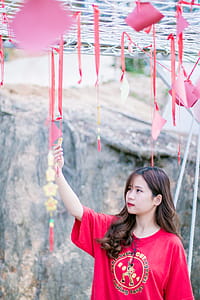 Woman Wearing Red Crew-neck Shirt Near Gray Wall thumbnail