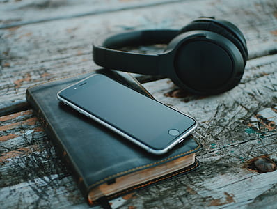 space gray iPhone 6 on top of black book beside wireless headphones thumbnail