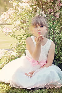 girl in white sleeveless dress sitting in front of plants during daytime thumbnail