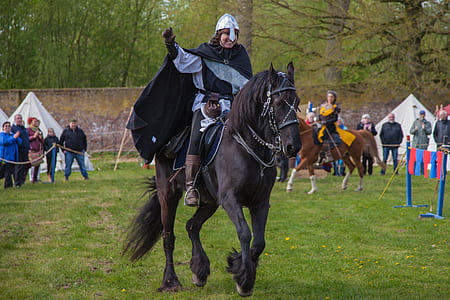 person wearing knight costume while riding black horse thumbnail