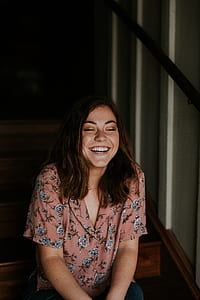 woman sitting on brown stairs while laughing thumbnail