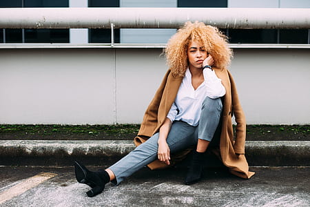 woman sitting on grey concrete pavement extending her feet holding her jaw thumbnail